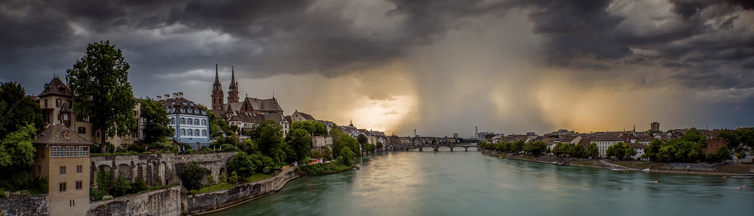 The Rhine at Basel under a breaking storm, the Minster on the skyline.