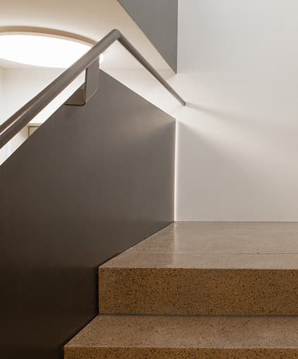 A stair landing in a renovated building, lit from a curved skylight.